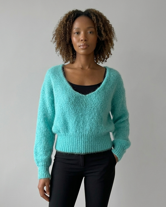South African model wearing light green mohair-blend sweater with fluffy knit texture, deep scoop neckline, oversized sleeves. Full body studio shot highlighting South African craftsmanship, Studio Minimale
