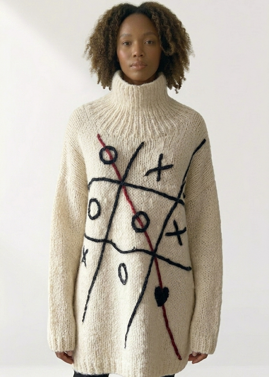 South African model wearing Tic Tac Toe Love Sweater in cream chunky knit with black X/O game graphic and red heart detail, oversized turtleneck silhouette. Studio Minimale South African craftsmanship